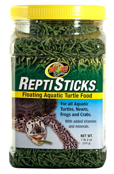 Clear plastic jar of green Zoo Med Reptisticks turtle food with a yellow lid and a label featuring a turtle eating a stick.
