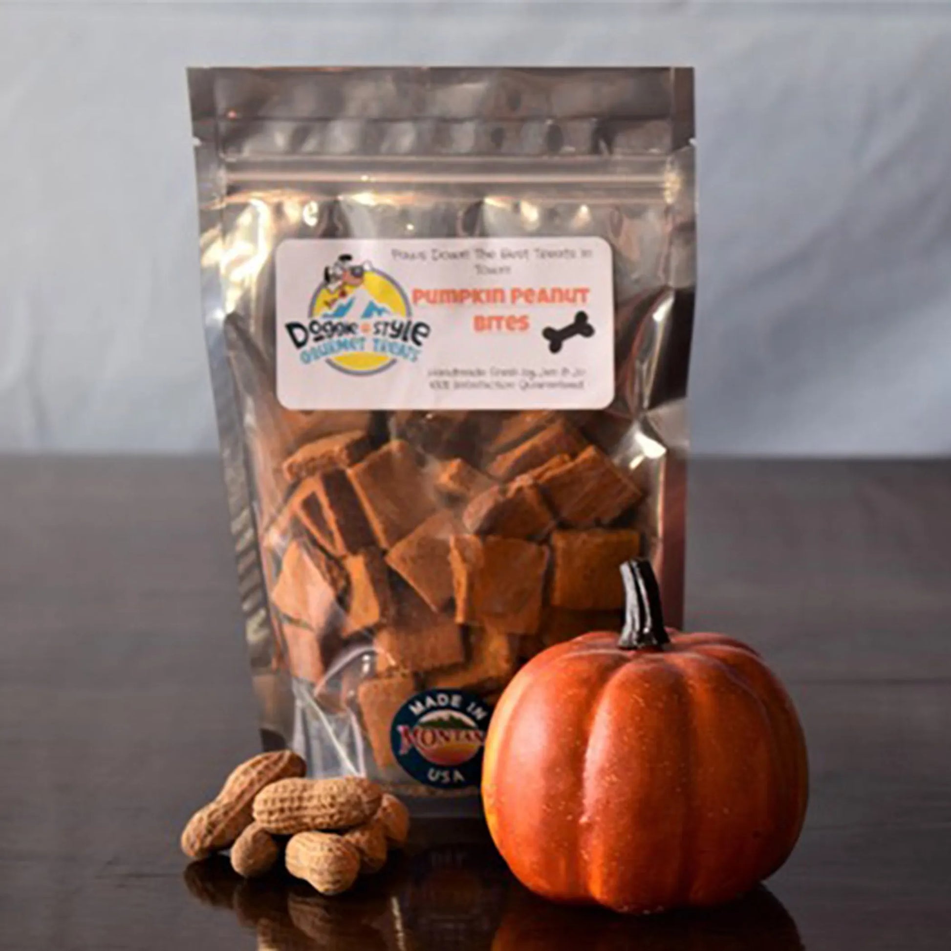 Clear resealable bag of Pumpkin Peanut Bites with peanuts and small pumpkin on wooden surface in natural light