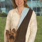 Woman outdoors carrying small dog in brown and blue ESC Reversible Sling Pet Carrier against office building backdrop