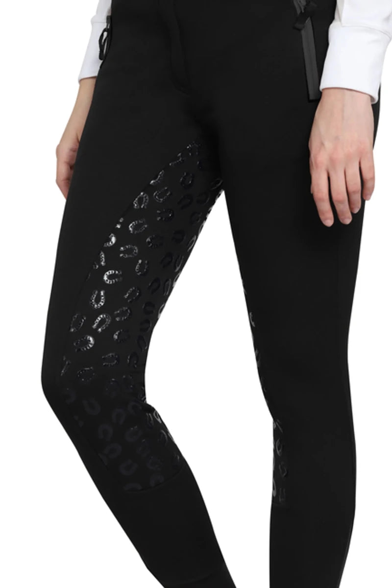 Close-up of a person wearing black TUFFRIDER LADIES MACY WINTER BREECHES with leopard print grip patches on inner legs.
