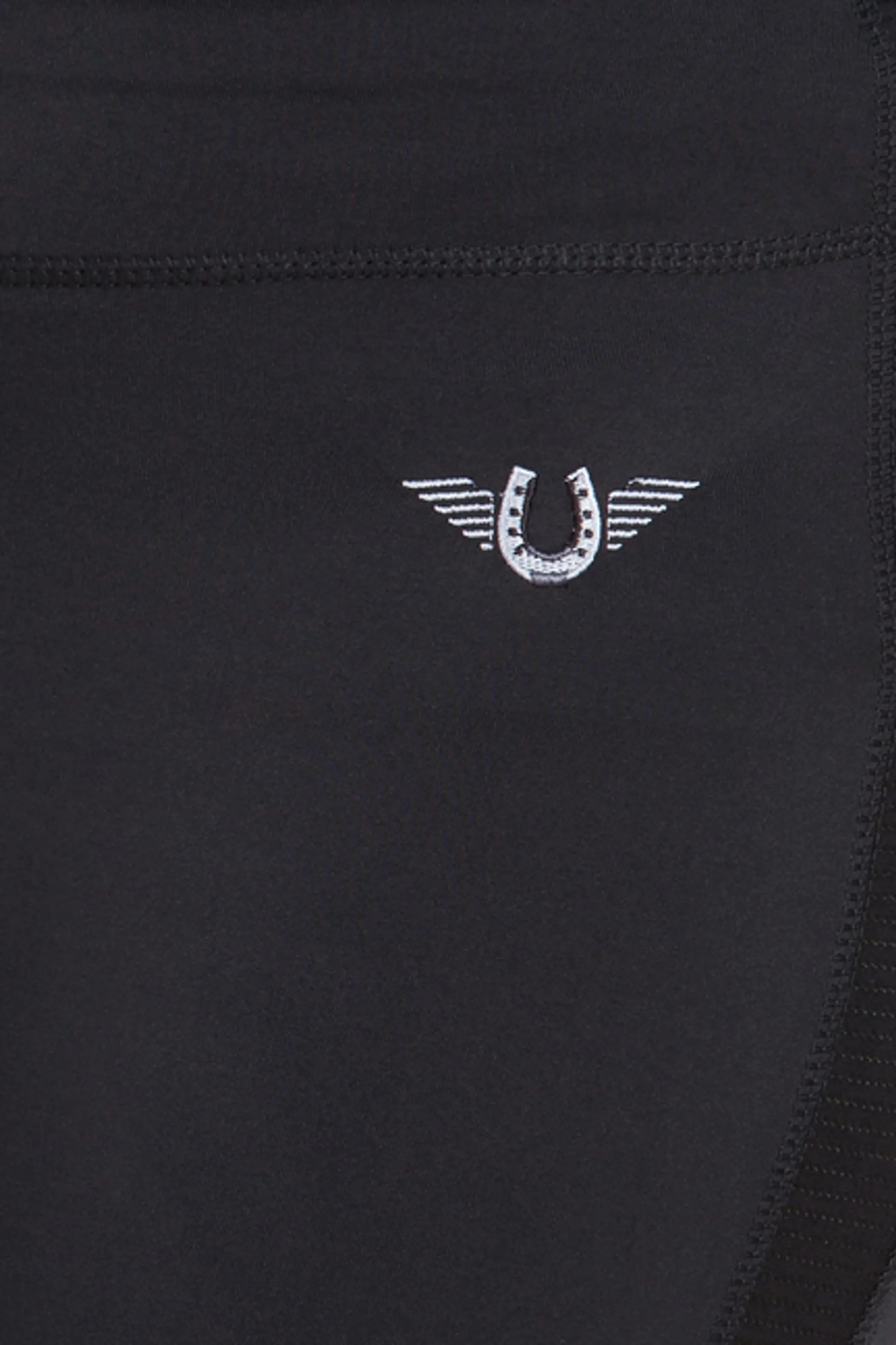 Close-up of black fabric with stitched horseshoe logo on TuffRider Ladies Ventilated Schooling Tights