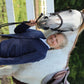 Young rider in TuffRider Children's Starter Show Coat standing beside a white horse outdoors by a fence