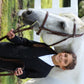 Child wearing TuffRider Children's Starter Show Coat standing next to white horse holding its bridle outdoors