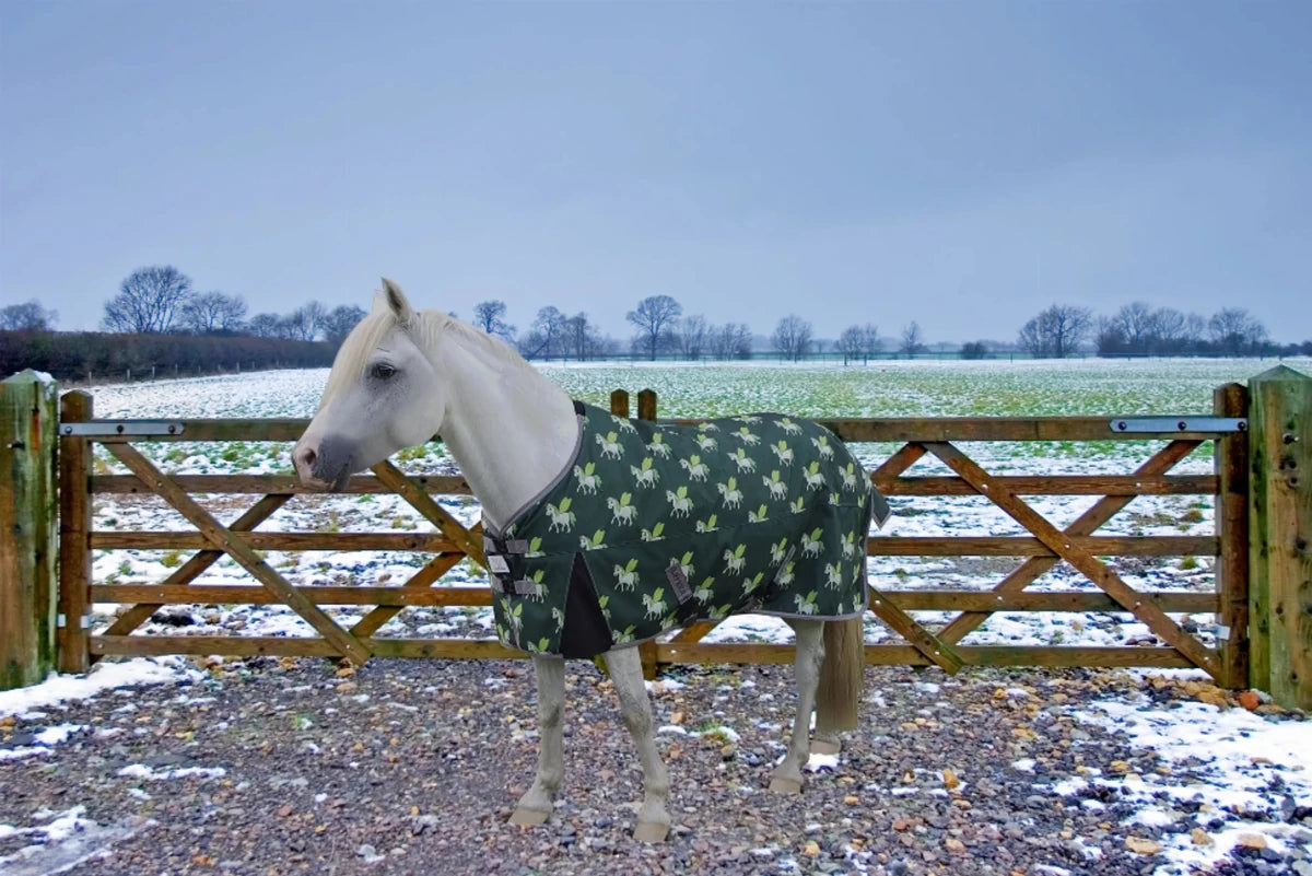 White horse wearing Waterproof Pony Turnout Blanket - 220g Insulated Winter Horse Blanket with Fun Print outdoors near a wooden gate.