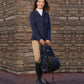 Woman in equestrian outfit holding Water-Resistant Backpack - Equestrian Gear Bag with Multiple Pockets against stone wall