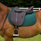 Brown leather Henri De Rivel Jaipur Polo Saddle on horse with green quilted saddle pad in outdoor setting
