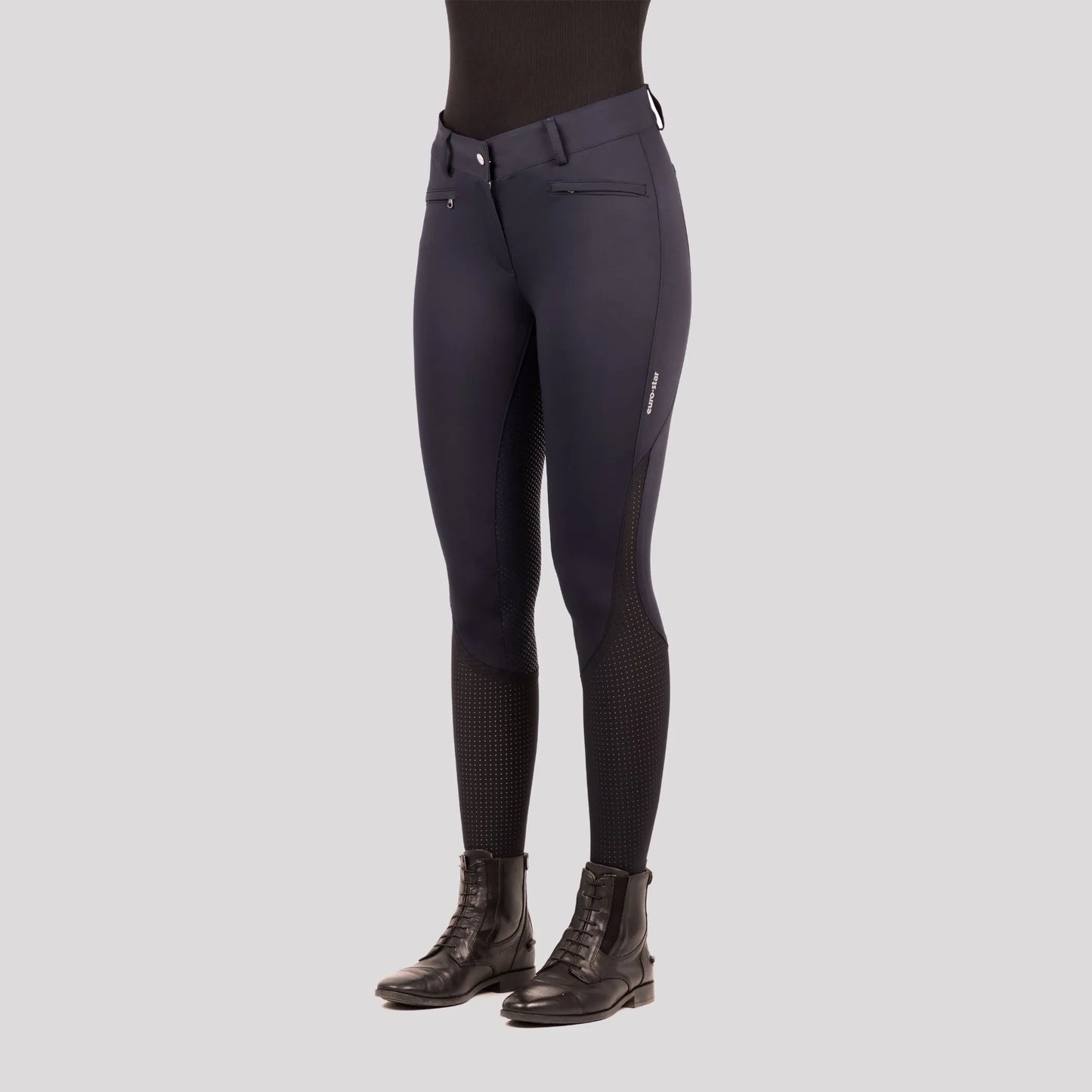 Close-up of a model wearing Euro-Star Riding Breeches ESAirflow FullGrip-Dark Berry-38 with riding boots in a studio setting