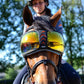 Horse wearing eQuick eVysor transparent reflective equestrian goggles with rider in helmet outdoors on sunny day
