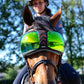 Horse wearing eQuick eVysor transparent green reflective fly mask with rider in background under blue sky