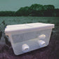 Clear plastic container with white lid and feeding ports designed as POULTRY PRO FEEDER for outdoor use on grass fields