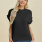 Woman wearing black Double Take Full Size Mock Neck Short Sleeve Sweater with jeans against neutral background