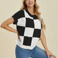 Woman wearing Double Take Full Size Checkered Round Neck Short Sleeve Sweater in black and white with blue jeans smiling