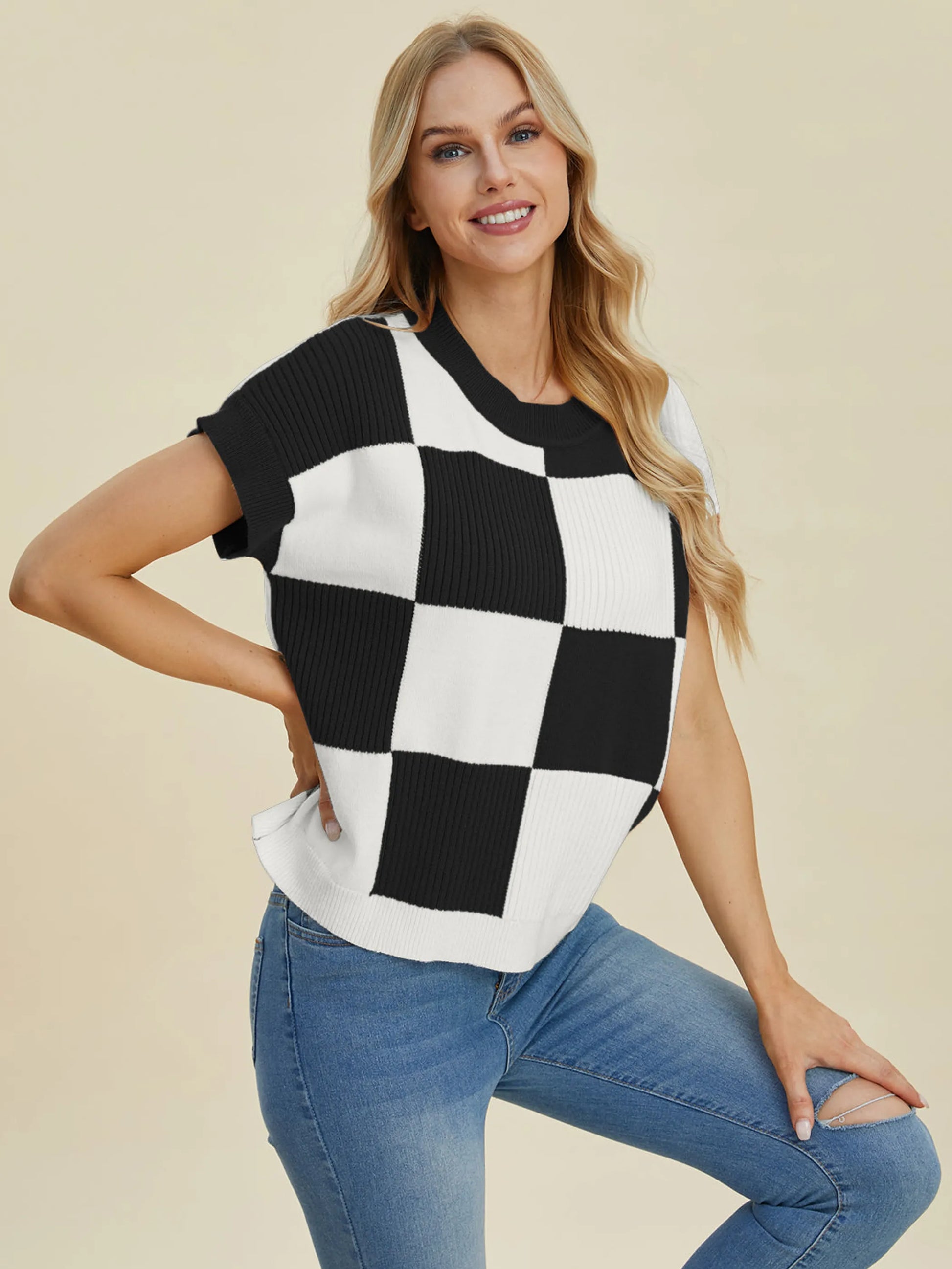 Woman wearing Double Take Full Size Checkered Round Neck Short Sleeve Sweater in black and white with blue jeans smiling