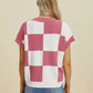 Woman wearing Double Take Full Size Checkered Round Neck Short Sleeve Sweater in pink and white checkered pattern from back view