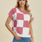 Woman wearing pink and white Double Take Full Size Checkered Round Neck Short Sleeve Sweater with blue jeans against neutral background