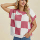 Woman wearing a pink and white Double Take Full Size Checkered Round Neck Short Sleeve Sweater with blue jeans smiling
