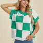 Woman wearing a green and white Double Take Full Size Checkered Round Neck Short Sleeve Sweater smiling with hand in pocket