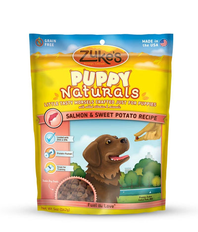 Yellow Zuke's Puppy Naturals treat bag with a brown puppy, a hand offering a treat, and product details.
