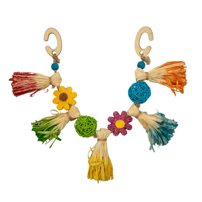 Colorful garland toy with straw tassels, woven balls, and flower shapes, hanging from two wooden hooks.