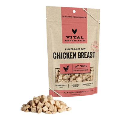 A bag of Vital Essentials freeze-dried chicken breast cat treats stands next to a pile of the light brown, cubed treats.
