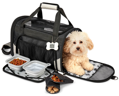 Small dog resting in Mobile Dog Gear Pet Carrier Plus with collapsible food and water bowls and treats pouch nearby