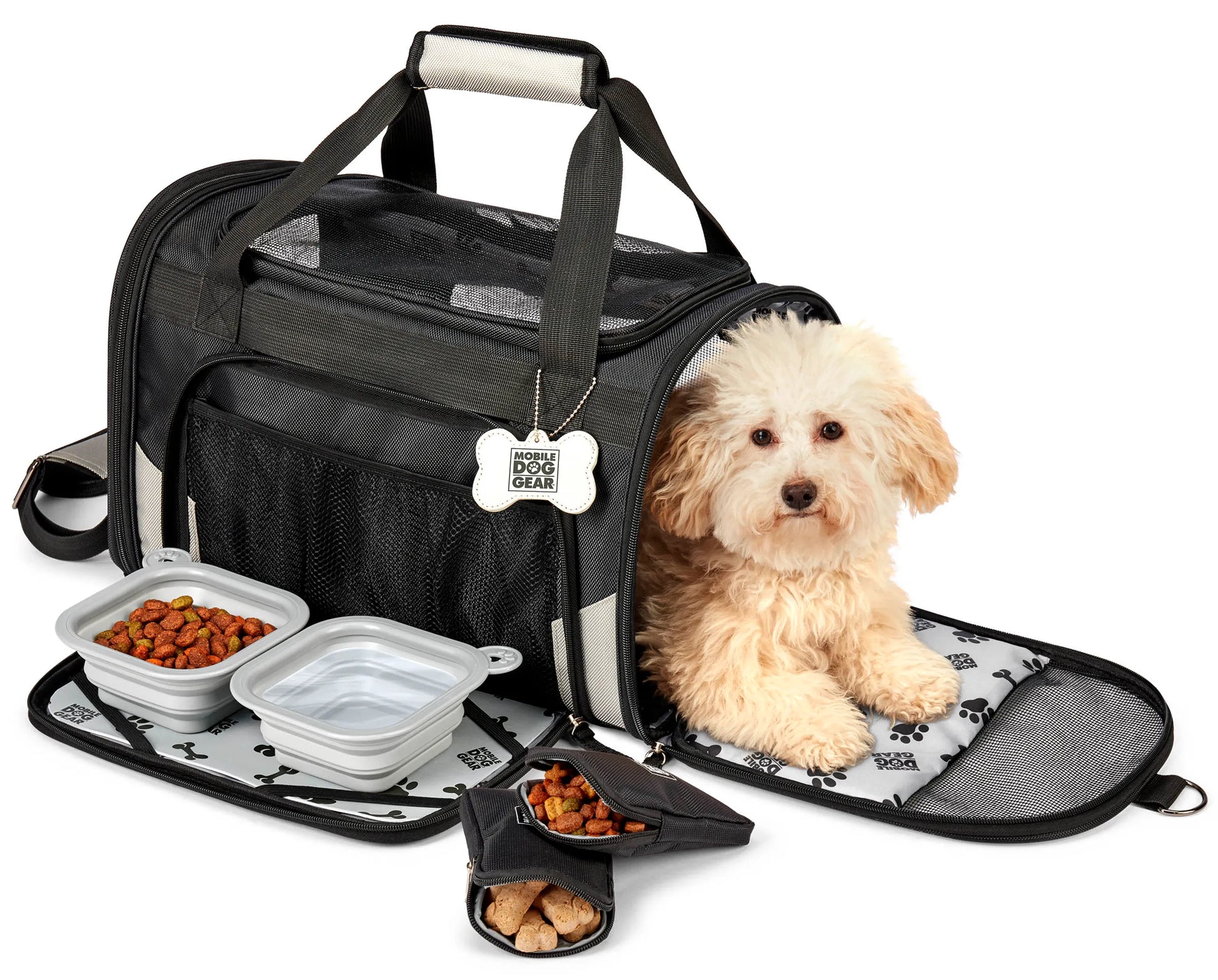 Small dog resting in Mobile Dog Gear Pet Carrier Plus with collapsible food and water bowls and treat pouch nearby