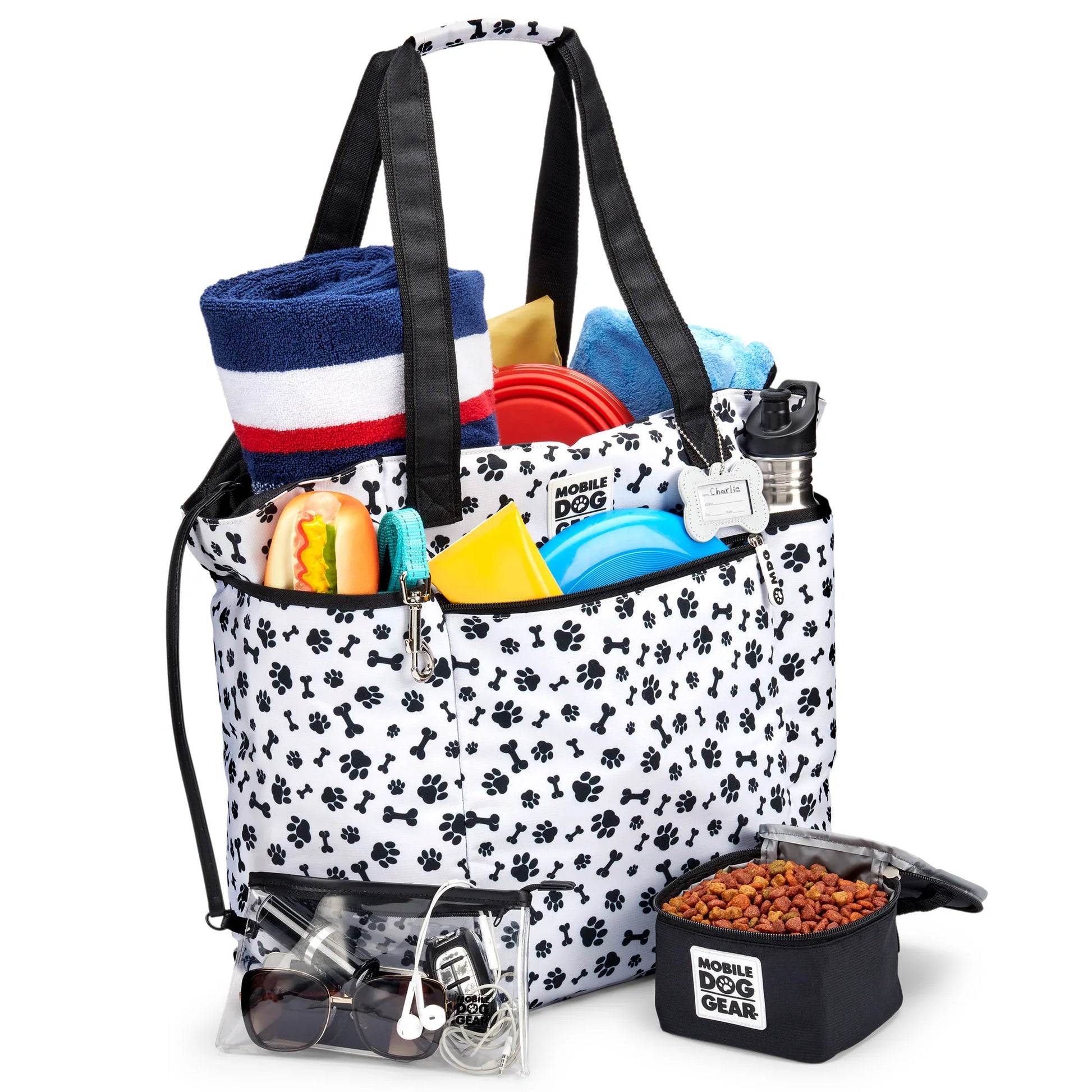 Mobile Dog Gear Dogssentials Tote Bag with paw print design filled with dog toys, bowls, towel, and accessories.